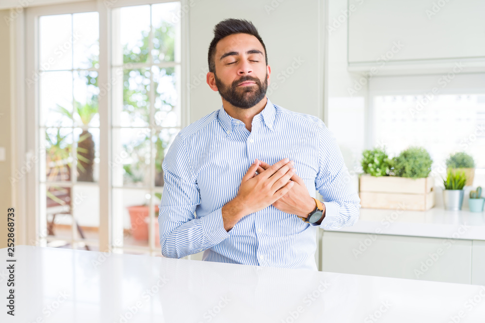 Handsome hispanic business man smiling with hands on chest with closed eyes and grateful gesture on face. Health concept.