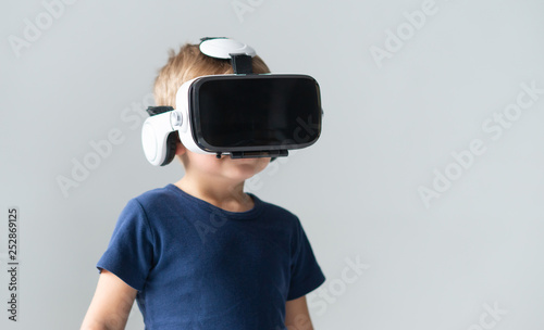 Portrait of happy boy in a virtual reality headset. Attractive kid using vr goggles at home. Entertainment technology and generation Z concept.