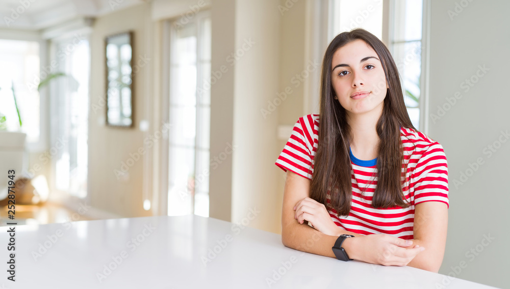 Beautiful young woman wearing casual stripes t-shirt with serious expression on face. Simple and natural looking at the camera. Beautiful young woman wearing casual stripes t-shirt with serious expression on face. Simple and natural looking at the camera.