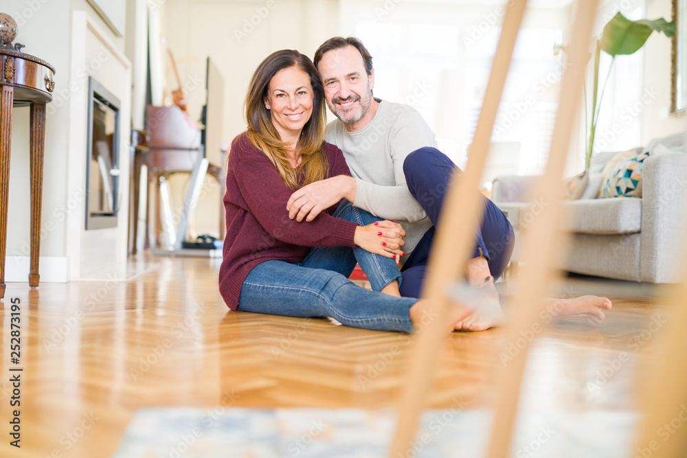 Beautiful romantic couple sitting together on the floor at home Beautiful romantic couple sitting together on the floor at home