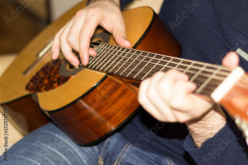 Classical guitar in the hands of a young guy.