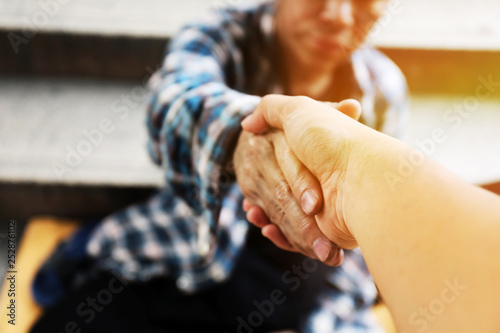Close-up handshake for help homeless man on walking street in the capital city. photo