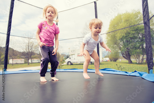 Two beautiful kids jumping on the trampoline and enjoying.