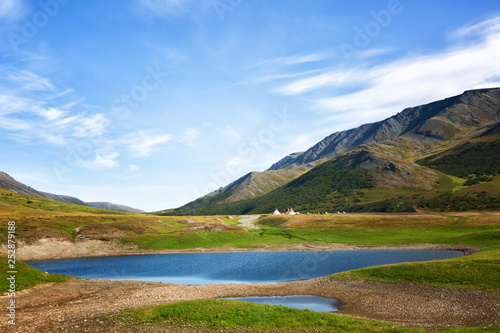 Landscape with a lake in the foreground, chums and mountains on a summer day