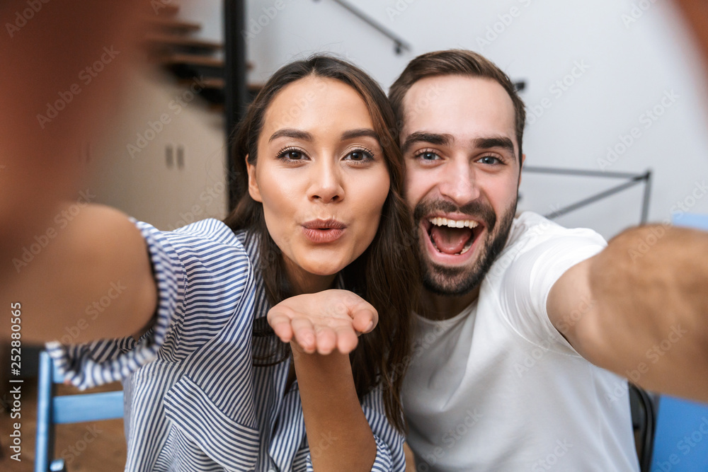 Cheerful multiethnic couple taking a selfie Cheerful multiethnic couple taking a selfie
