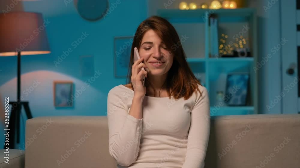 Portrait of the attractive young woman talking on the phone cheerfully with a friend while sitting at home in the evening. Indoor, good news Portrait of the attractive young woman talking on the phone cheerfully with a friend while sitting at home in the evening. Indoor, good news