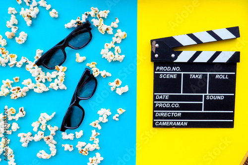 Popcorn and clapperboard on colorful background. photo