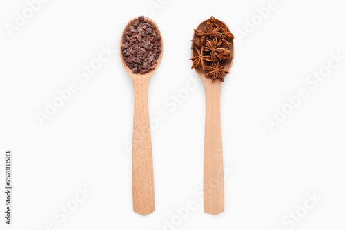 Wooden spoons with anise and black Indian salt on white