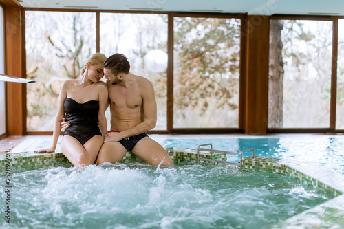 Loving couple relaxing in the spa by swimming pool