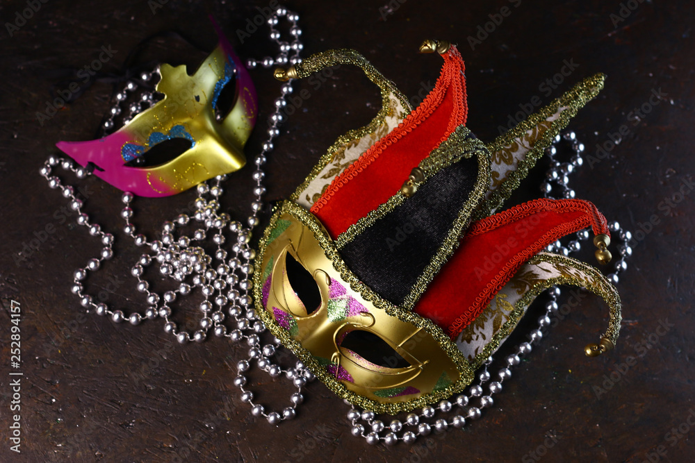 Carnival venetian Joker masks and silver beads on dark background. Carnival masks side view.