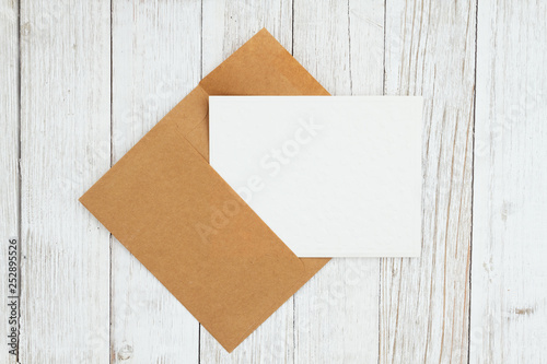 Blank envelope with greeting card on weathered whitewash textured wood background