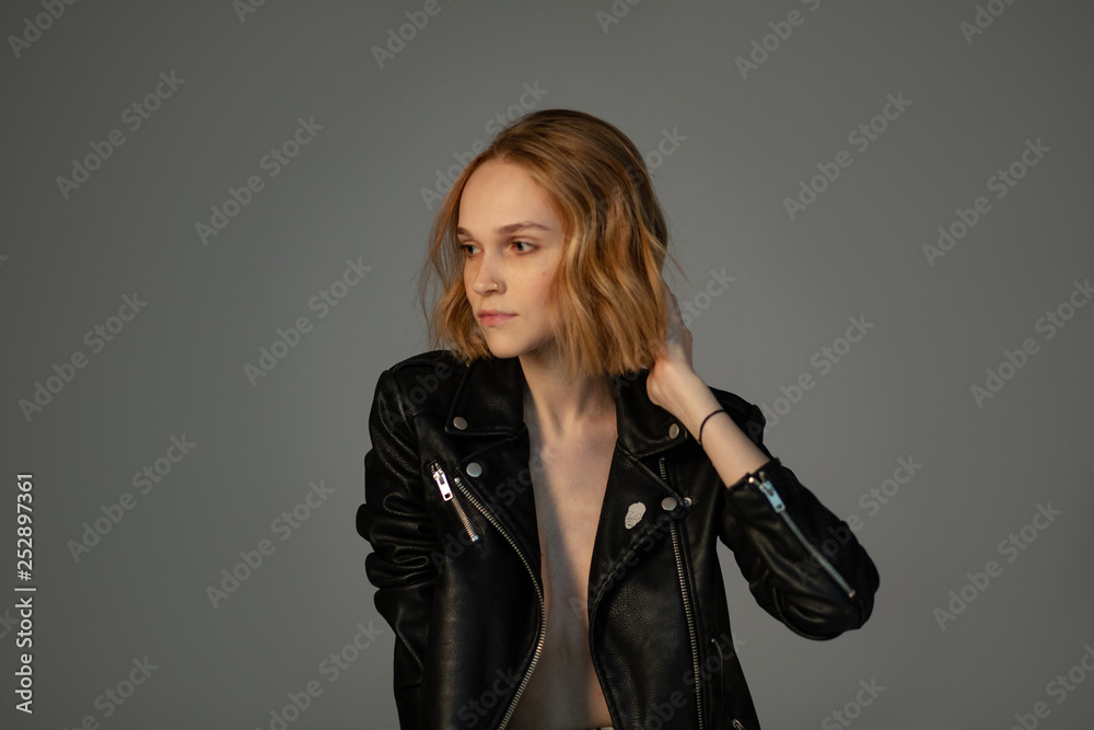 Half length portrait of beautiful girl in black leather jacket that touching her hair Half length portrait of beautiful girl in black leather jacket that touching her hair