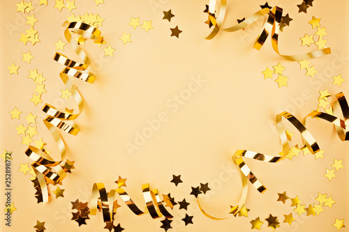 Background about a party, confetti, stars and streamers. Made in gold shades. Copy space. Top view