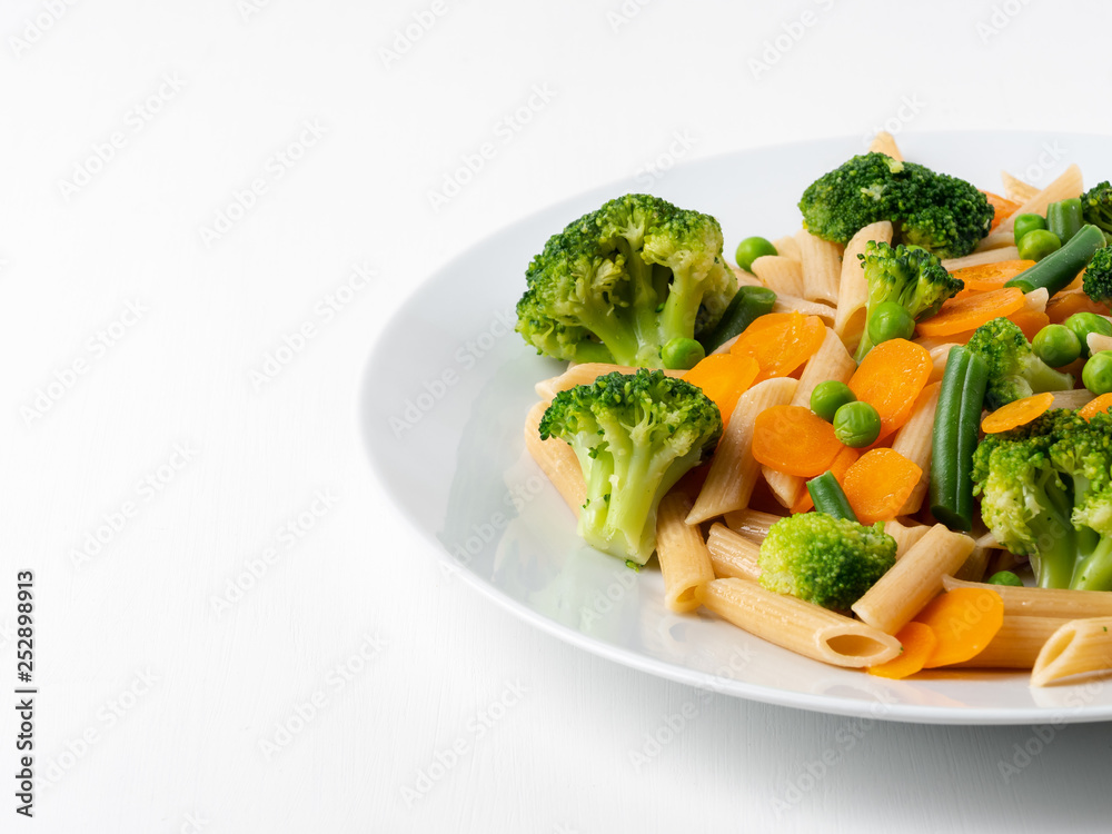 Whole wheat pasta Penne with broccoli, carrots, green peas. Part of plate. Diet menu, proper nutrition, healthy food Whole wheat pasta Penne with broccoli, carrots, green peas. Part of plate. Diet menu, proper nutrition, healthy food