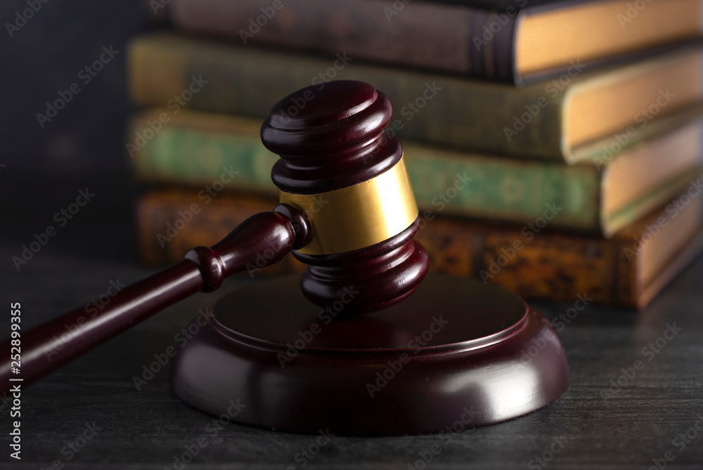 Judges Gavel on a Desk with Books in the Background Judges Gavel on a Desk with Books in the Background