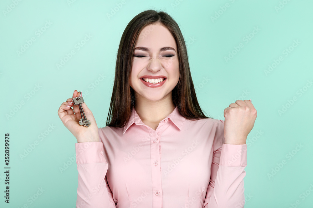 Obraz premium Young woman showing house keys on mint background