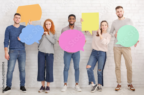 Happy friends holding speech bubbles over white wall photo