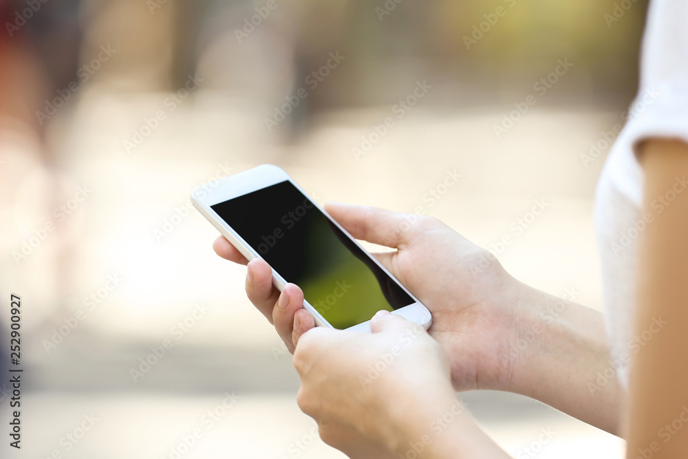 Woman holding and using smartphone on blurred background