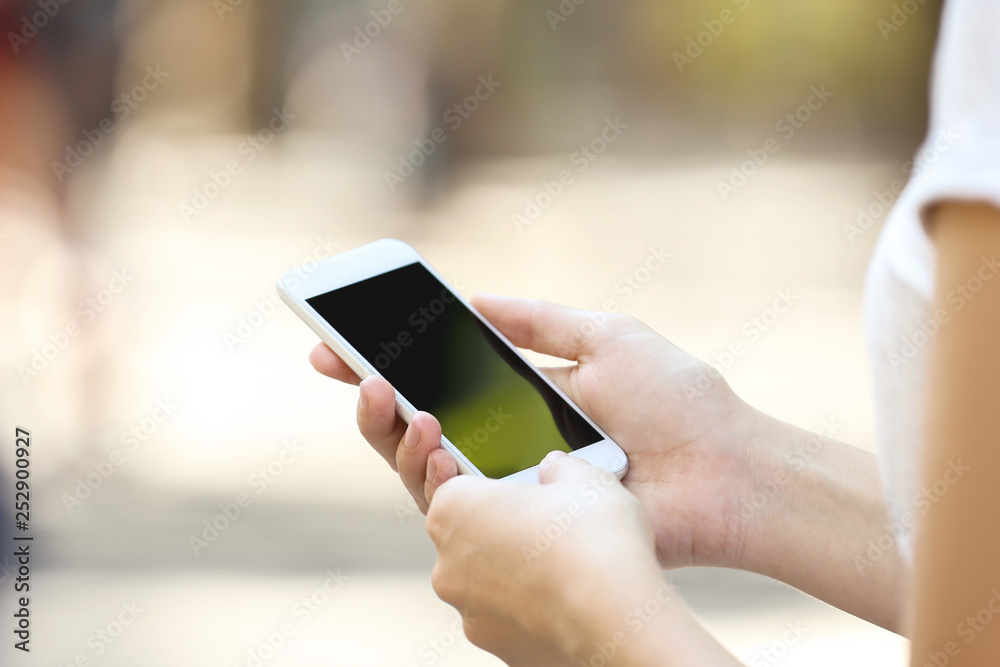 Woman holding and using smartphone on blurred background Woman holding and using smartphone on blurred background