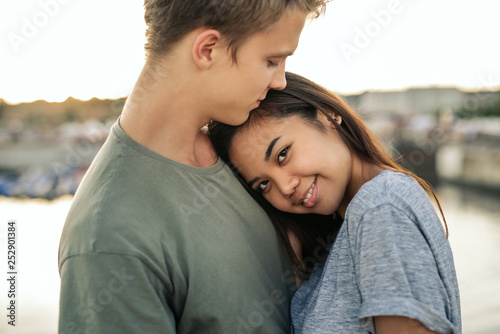 Smiling young woman hugging her boyfriend outside by a harbor