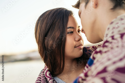 Young couple wrapped in a blanket about to kiss outside