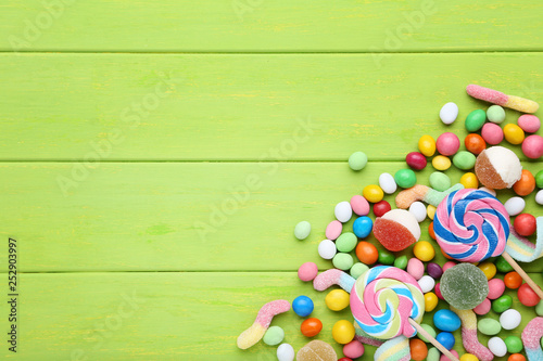 Sweet candies and lollipops on green wooden table