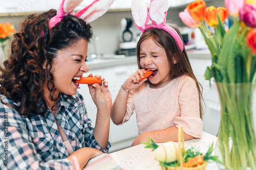 Mother and her cute little daughter having fun in kitchen while preparing Easter eggs.