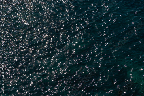 Sun glare on dark water. Surface of sea in Sunny weather, top view.