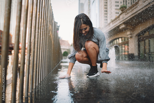 girl playing and dancing around on a wet street of Chicago