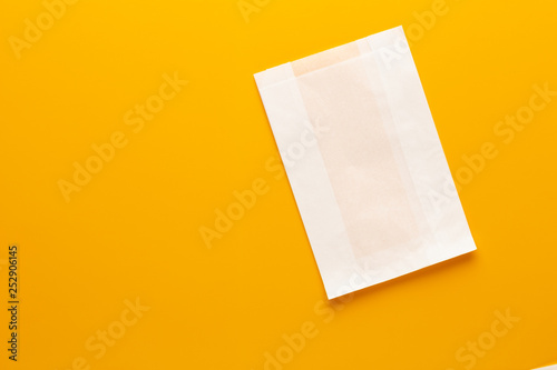 White paper bag on yellow background.