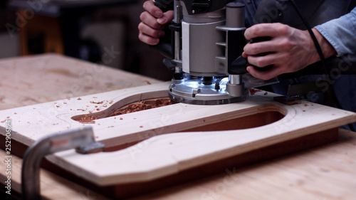 Obraz na plátně Luthier makes a hole in a piece of wood for guitar