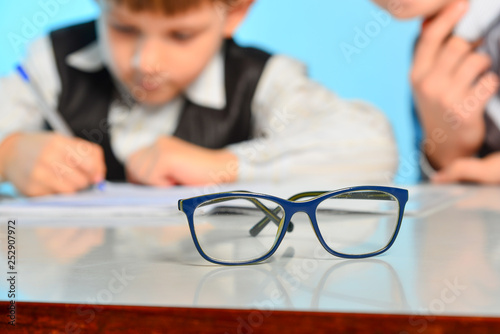 Glasses for sight against the background of children making lessons in school