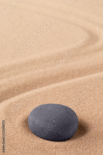 Zen meditation stone to focus and concentrate for a quit peace of mind. Spiritual raked sand background texture. Concept for harmony purity and spirituality.