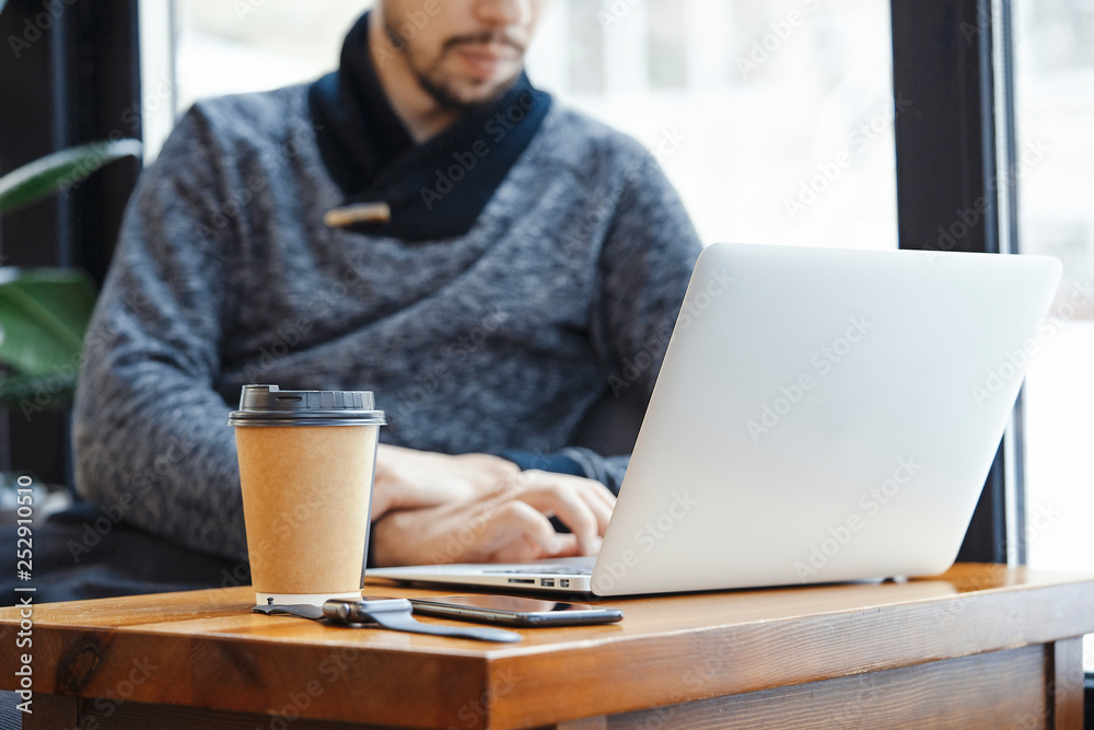Attractive man with laptop and modern electronic watches in modern bright cafe. Attractive man with laptop and modern electronic watches in modern bright cafe.