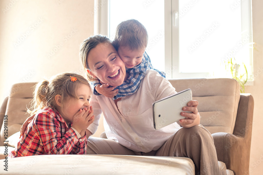Happy family, mother with children watching cartoons on tablet and having fun at home