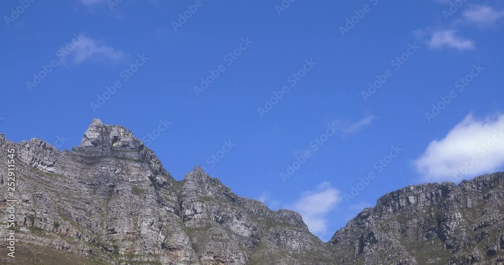 Time lapse of puffy clouds sailing over jagged mountain ridge in Capetown Time lapse of puffy clouds sailing over jagged mountain ridge in Capetown