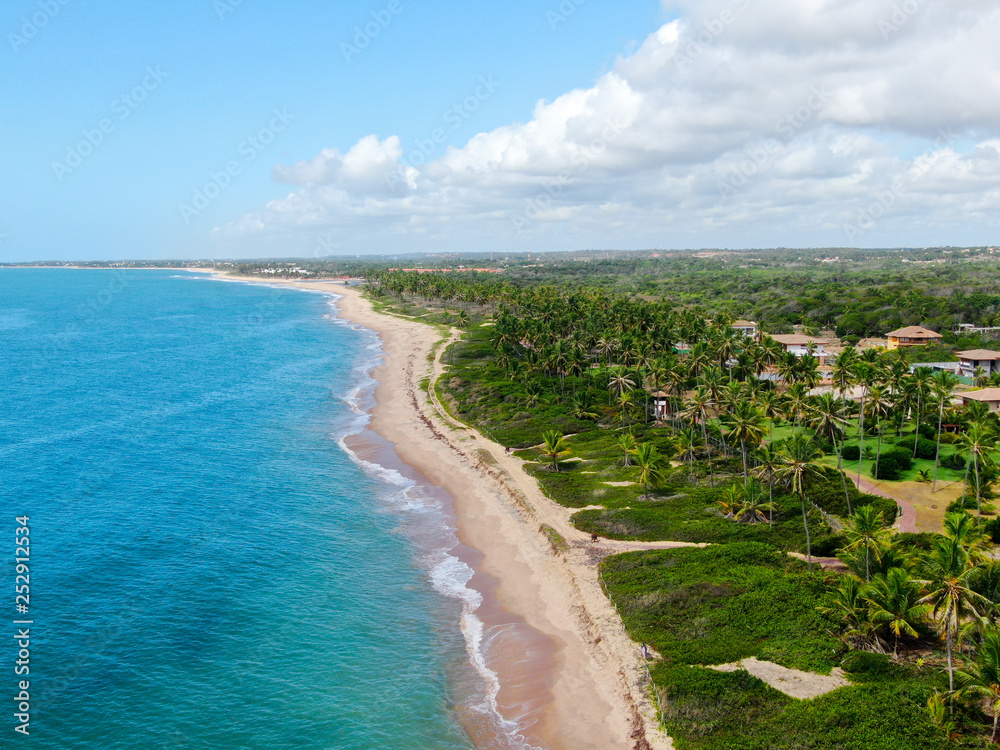 Aerial view of tropical white sand beach and turquoise clear sea water with small waves and palm trees background. Praia do Forte, Bahia, Brazil. Travel tropical concept