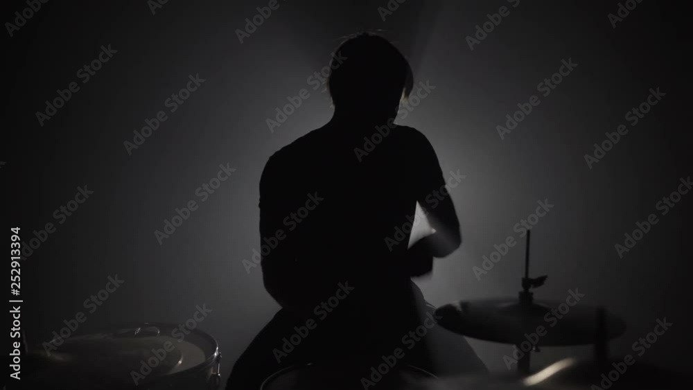 Silhouette of male drummer playing drums in dark Silhouette of male drummer playing drums in dark