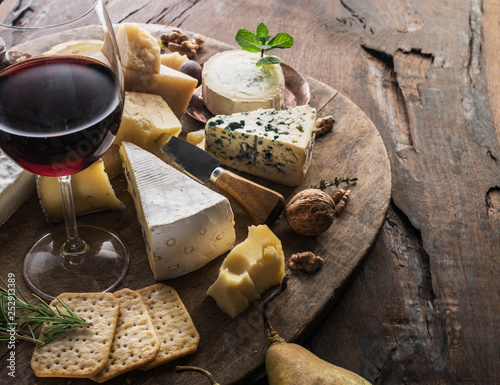 Fotografía Cheese platter with organic cheeses, fruits, nuts and wine on wooden background