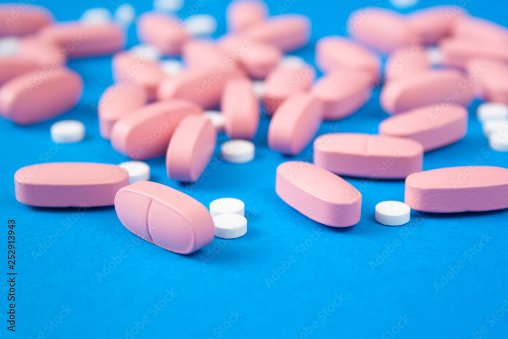 White and pink pills on blue background. Medicine and healthcare concept