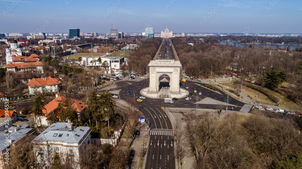 Aerial view of an arch and boulevards surrounding it on a sunny day in Bucharest.