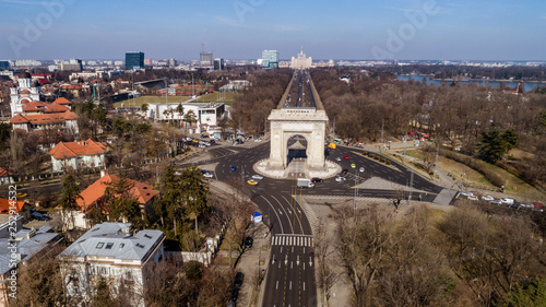 Aerial view of an arch and boulevards surrounding it on a sunny day in Bucharest.