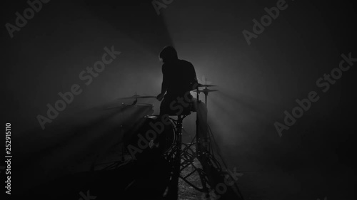 Silhouette of male drummer playing drums in smoke