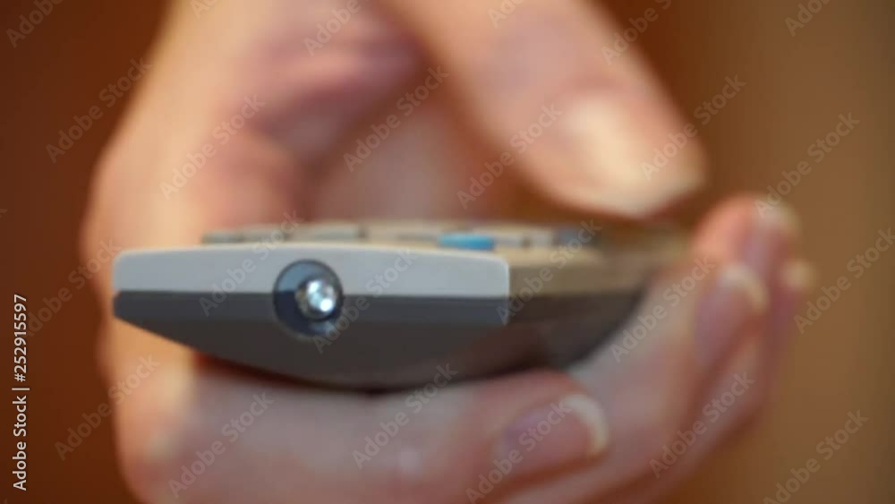Watch TV and use the remote control. Girl presses the buttons of the remote, close-up, macro Watch TV and use the remote control. Girl presses the buttons of the remote, close-up, macro