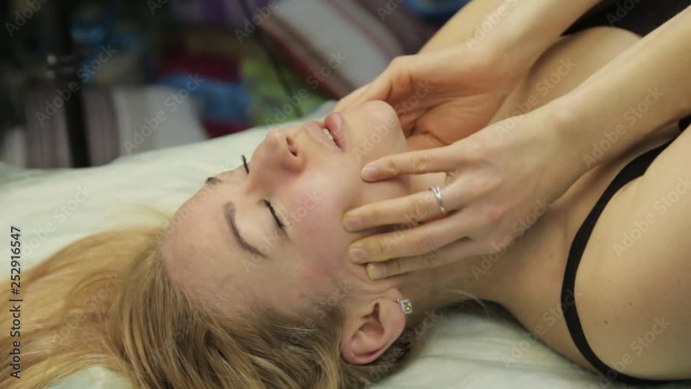 blonde woman doing self-massage, facial massage lying in bed at home blonde woman doing self-massage, facial massage lying in bed at home
