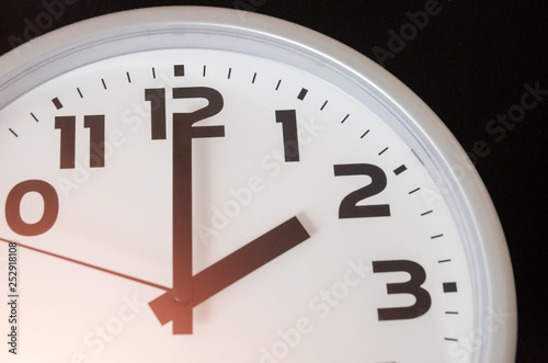 Close up of black and white analog clock with selective focus at 2 Oclock with flare. Time concept