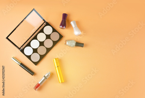 Cosmetics lies on a soft peach background. Contents of women's cosmetic bag