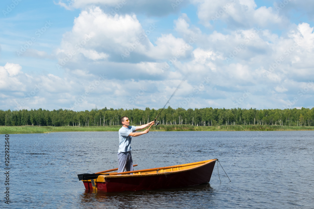 a man from a boat on the river is fishing for spinning, outdoor activities a man from a boat on the river is fishing for spinning, outdoor activities