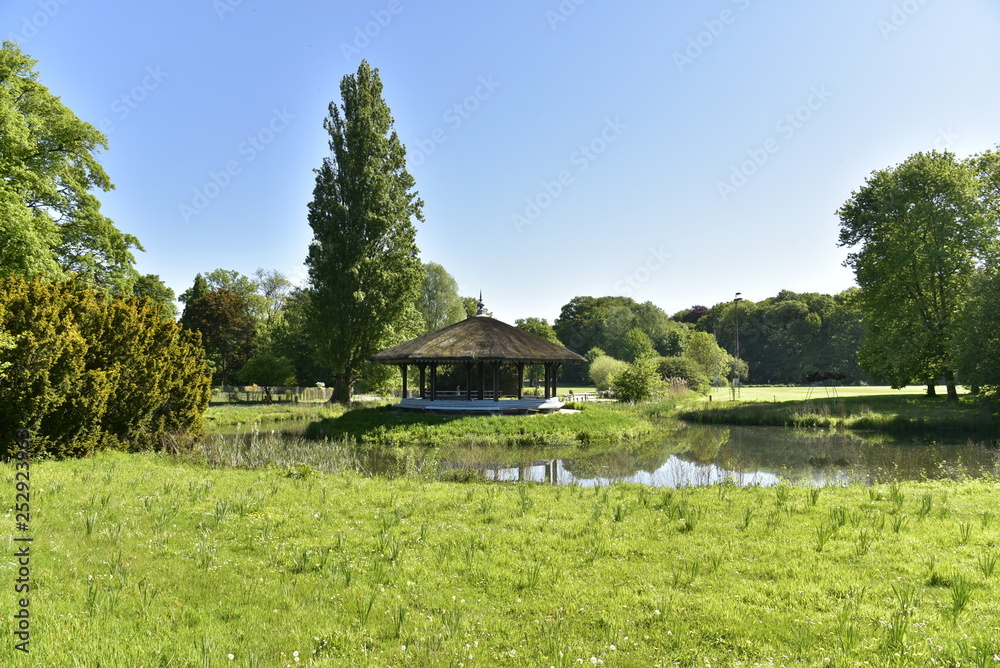 L'étang entourant l'abris en toit de chaume près du conifère majestueux au domaine provincial de Rivierenhof à Anvers L'étang entourant l'abris en toit de chaume près du conifère majestueux au domaine provincial de Rivierenhof à Anvers