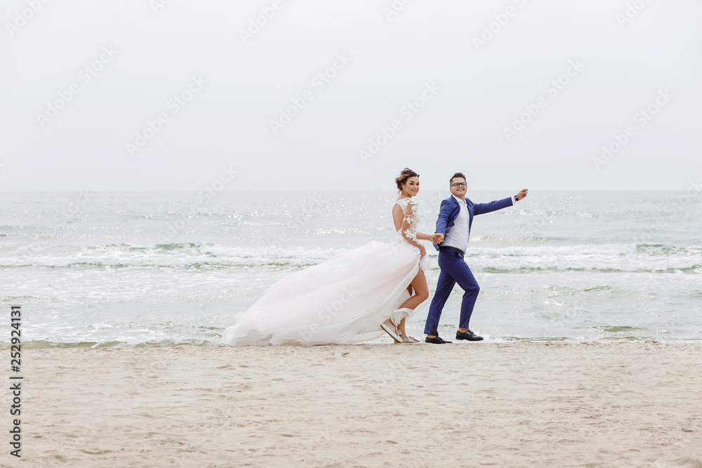 newlyweds run along the beach along the sea in cloudy weather newlyweds run along the beach along the sea in cloudy weather